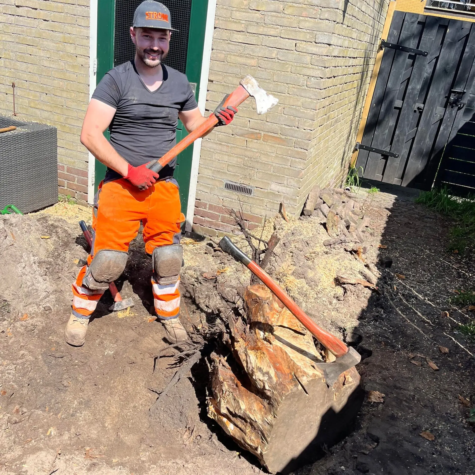 Vakman van Stronk aan het werk met een bijl bij een boomstobbe